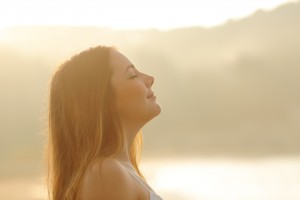How to Increase Alkalinity in Body - Backlight profile of a woman breathing deep fresh air in the morning sunrise isolated in white above
