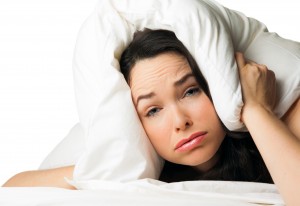 Reset Your Body Clock - A tired sleepless woman with the pillow over her head . Isolated over white.